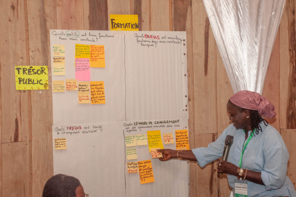 Photo d'une femme travaillant sur un poster illustrant l'importance de la formation pour l'émancipation des femmes rurales